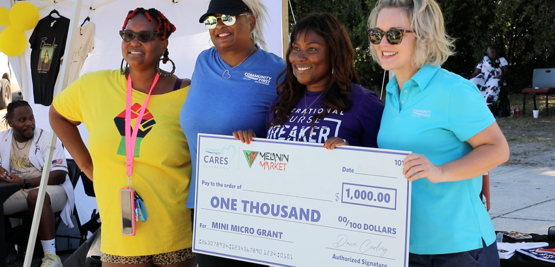 Women holding a large check awarded to minority-owned businesses by Jax Melanin Market and Community First Cares Foundation
